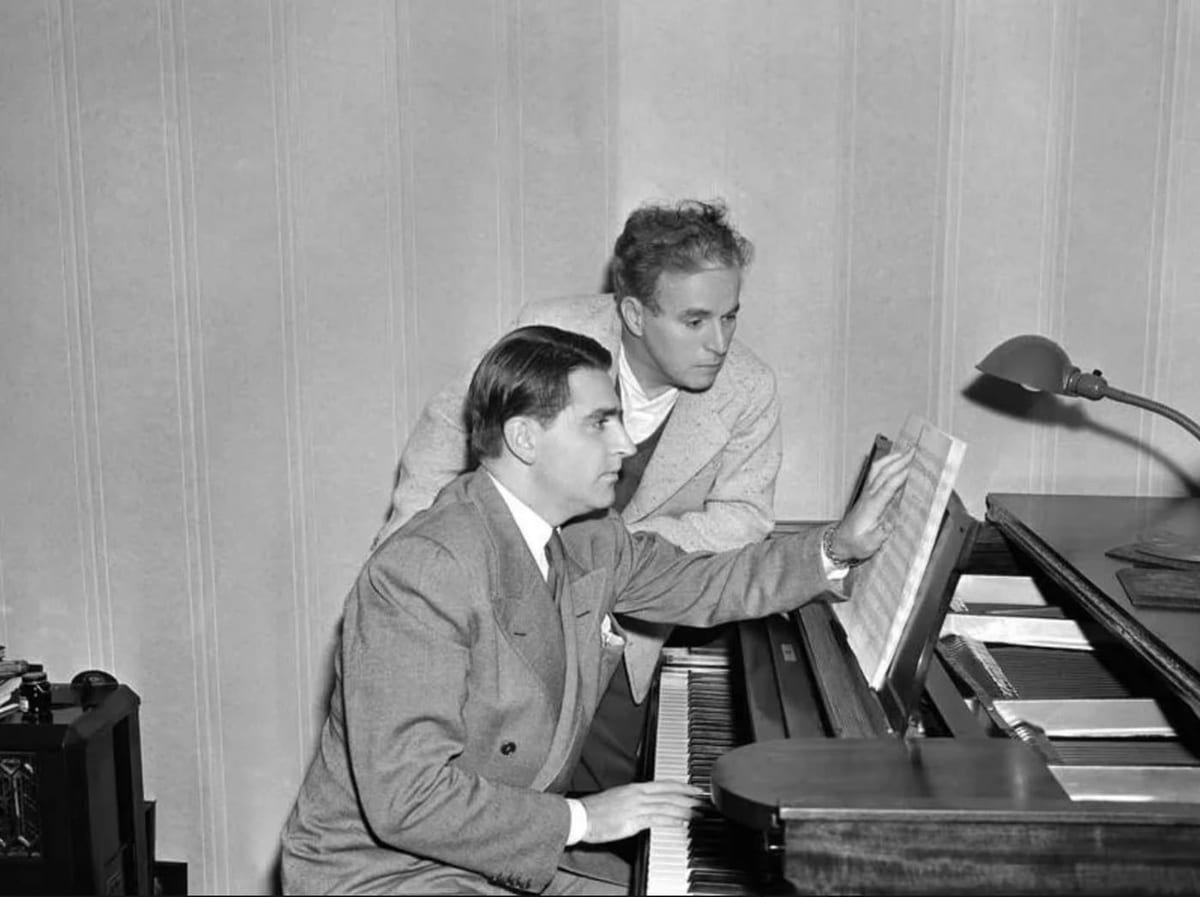 Charlie Chaplin dirige le compositeur Meredith Willson au piano, lors de leur travail sur la musique du « Dictateur » (1940).