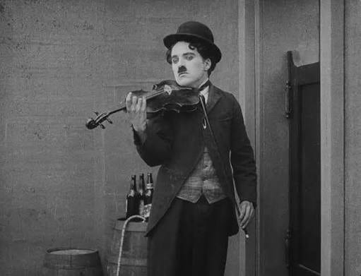 Charlie Chaplin violoniste, dans une scène du film « The Vagabond » (1916) : autodidacte, il jouait du violon et composa plus tard la musique de ses films.