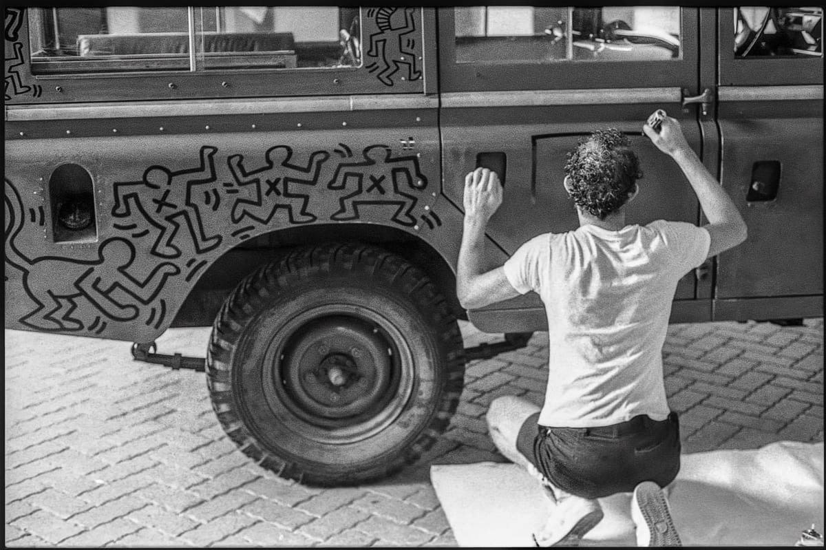 Keith Haring dessine sur la Land Rover, en juillet 1983. Photo Edouard Curchod.