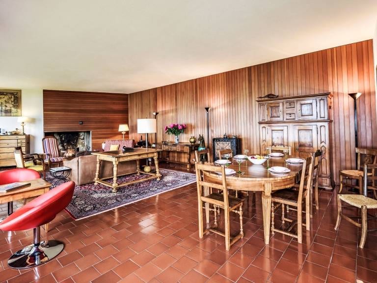 Le grand salon lambrissé et sa cheminée, prolongé par la salle à manger.
