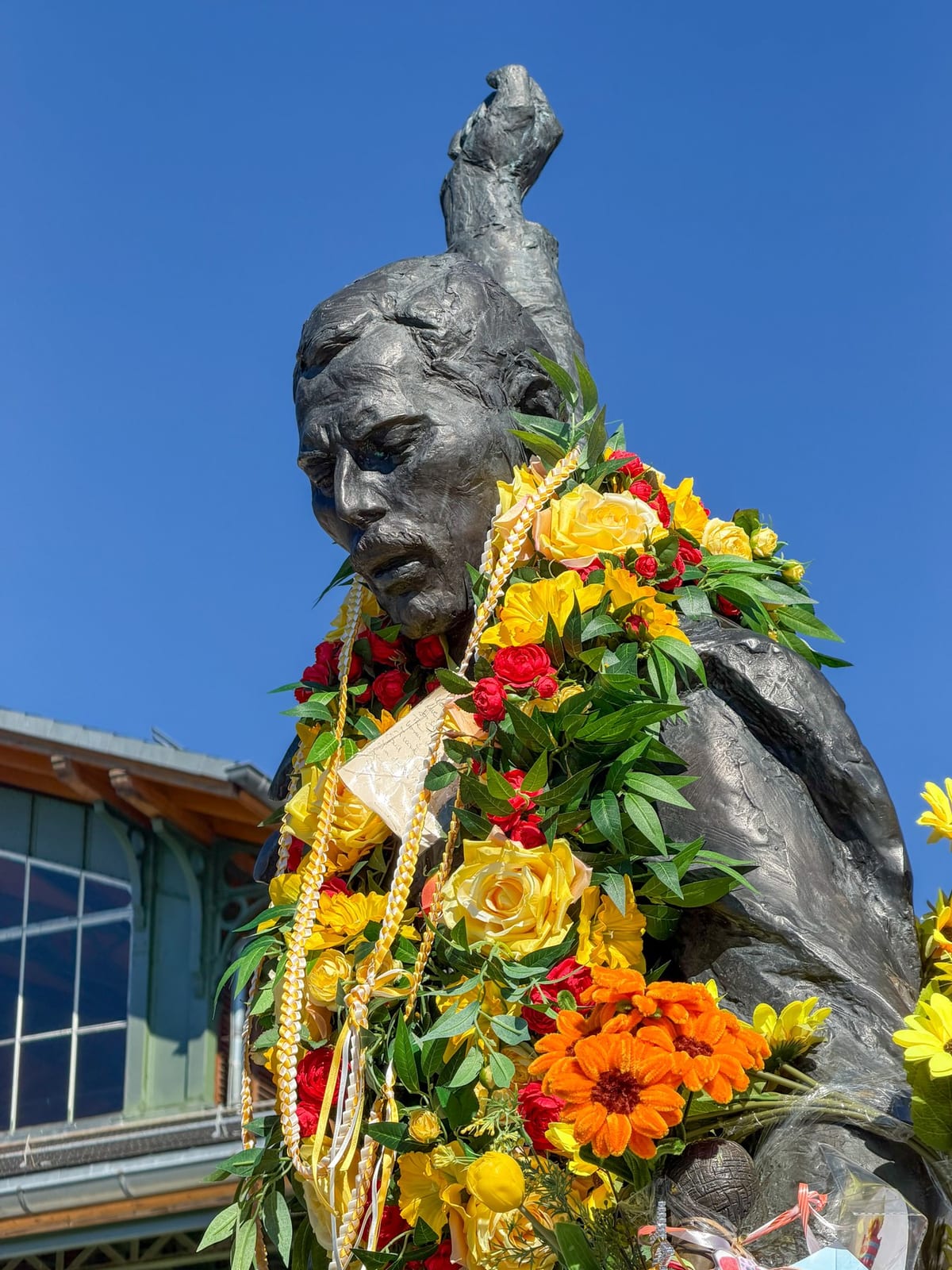 Le visage de bronze de Freddie sous les guirlandes de fleurs.