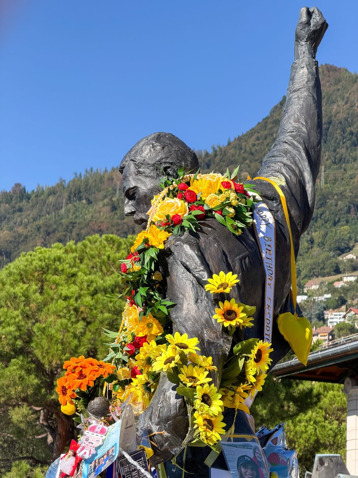 Le bras levé de la statue, couvert de fleurs.