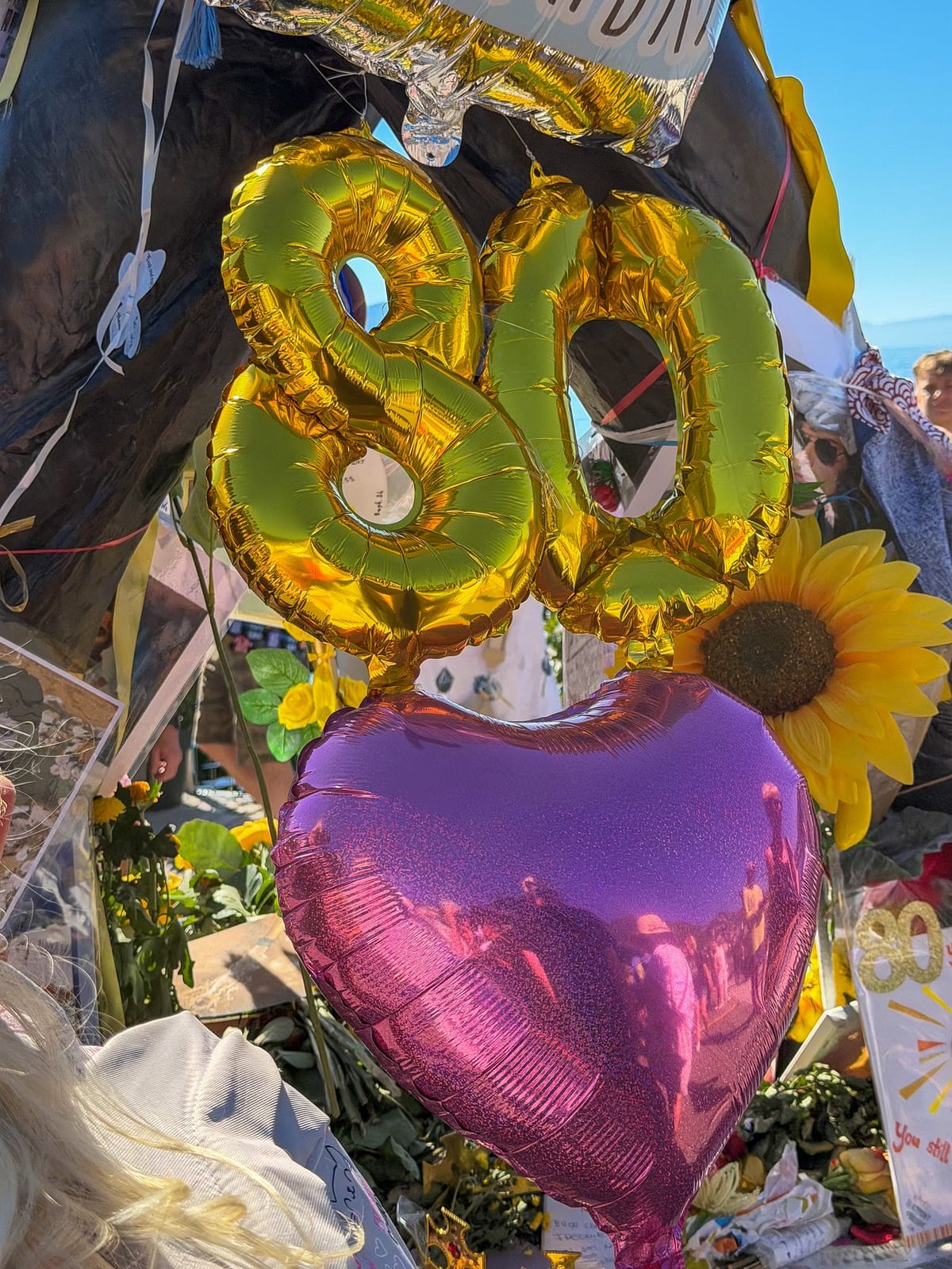 Des ballons dorés « 80 » et un cœur, au pied de la statue.