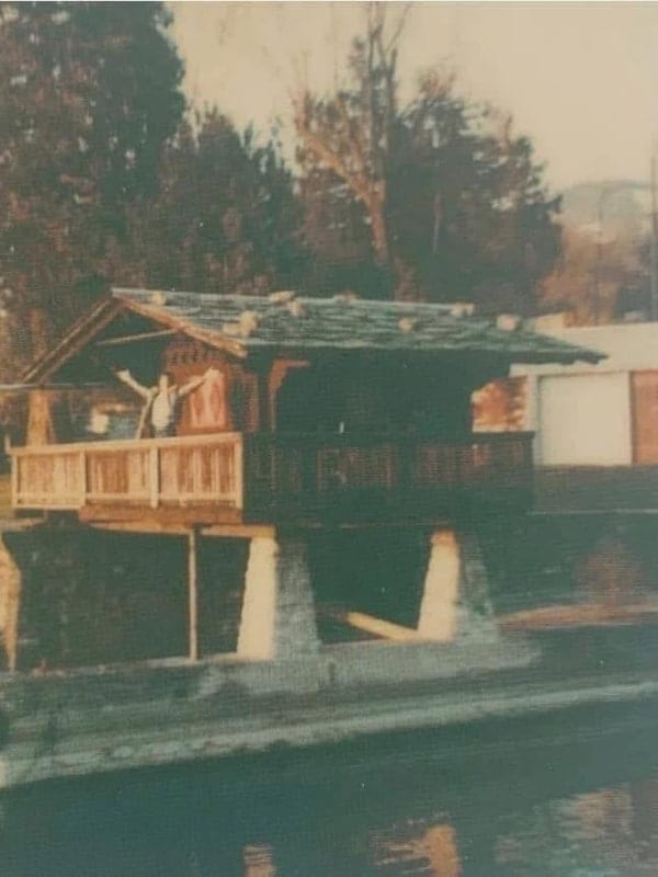 Freddie Mercury, bras levés, sur la petite cabane au bord du lac de la Duck House, la villa de Clarens qu’il louait.