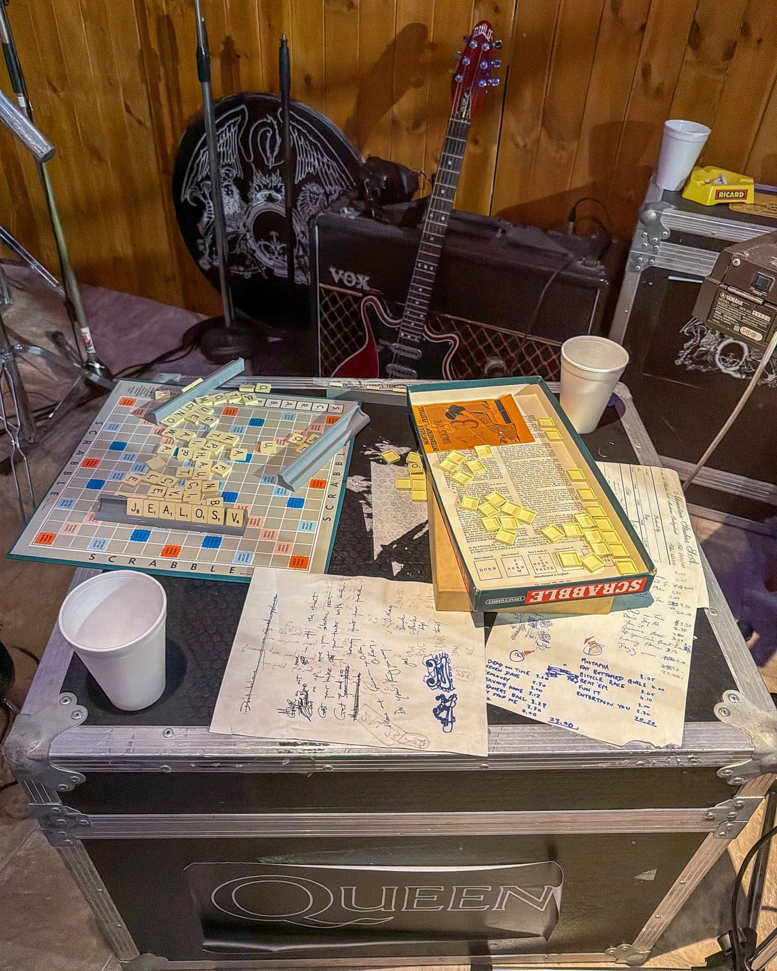 Le plateau de Scrabble du groupe et des feuilles de setlist, posés sur une malle de tournée Queen.